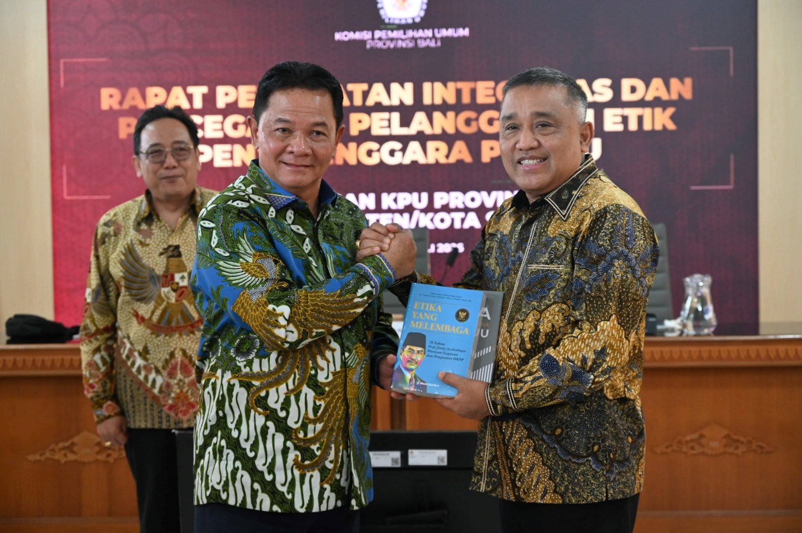 Ketua DKPP RI Heddy Lugito menyerahkan buku kepada Ketua KPU Bali Lidartawan dalam rapat penguatan integritas penyelenggara Pemilu