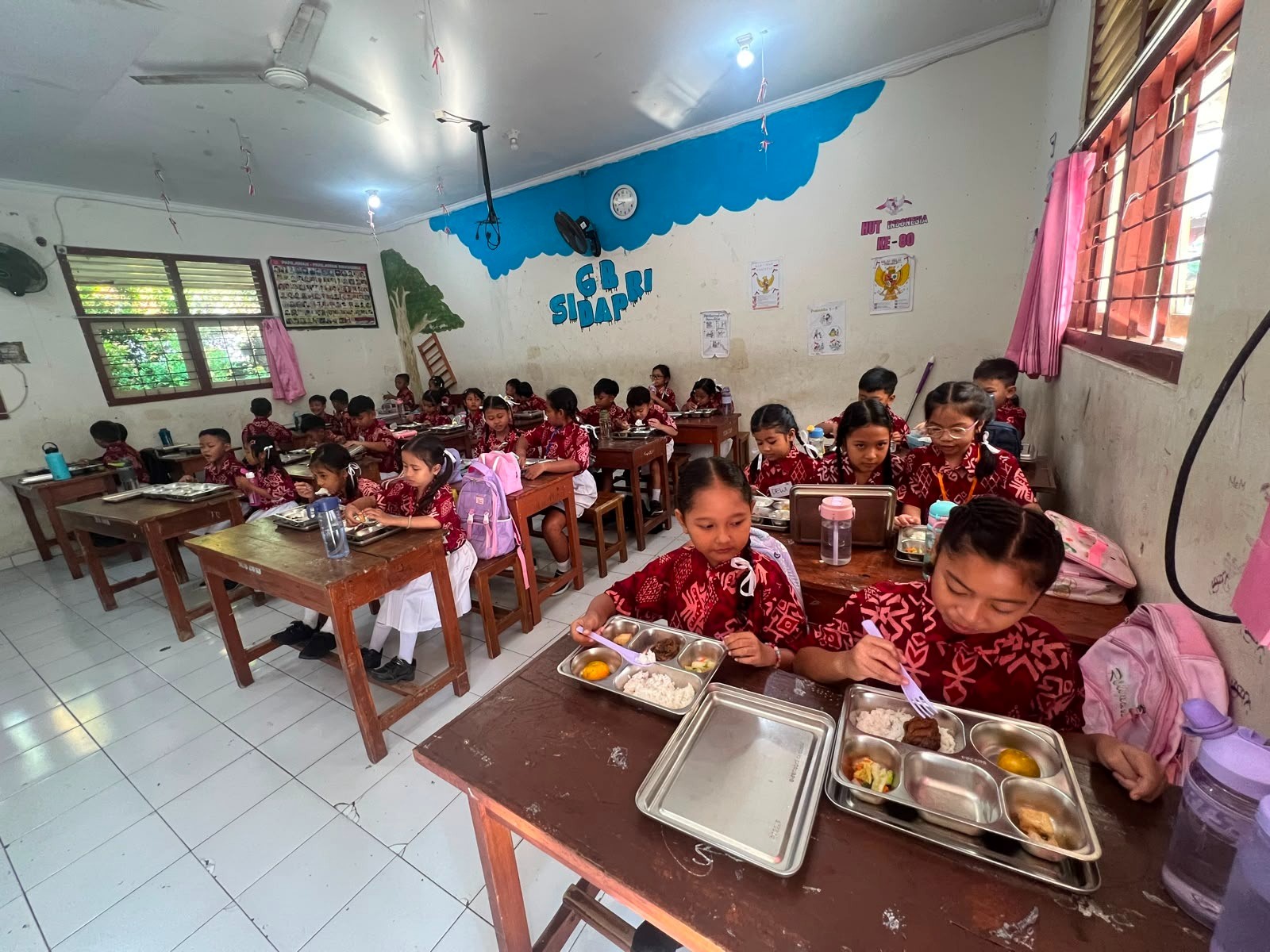 Petugas SPPG Polresta Denpasar menyalurkan program Makan Bergizi Gratis kepada siswa SD Negeri 7 Dauh Puri di Denpasar.