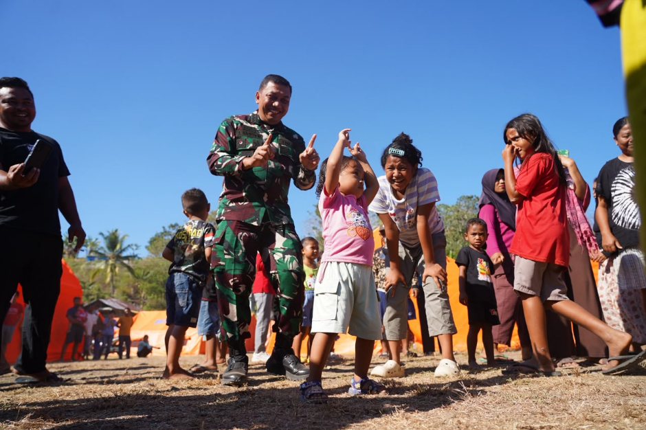 Kepala Penerangan Kodam IX/Udayana Kolonel Inf Amrizal Nasution berinteraksi dengan anak-anak korban gempa di posko pengungsian Lapangan Golo Congo, Kecamatan Reok, Kabupaten Manggarai.